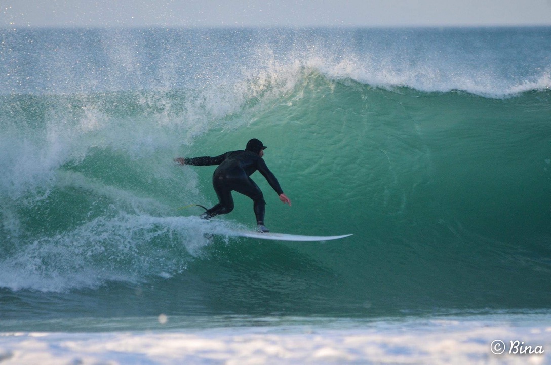 Surfeur debout sous la lèvre d’une vague verte